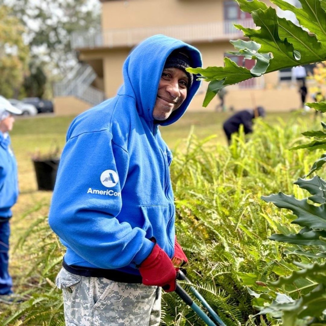 AmeriCorps Seniors volunteer clears landscaping during a community beautification project with Seniors in Service volunteers.