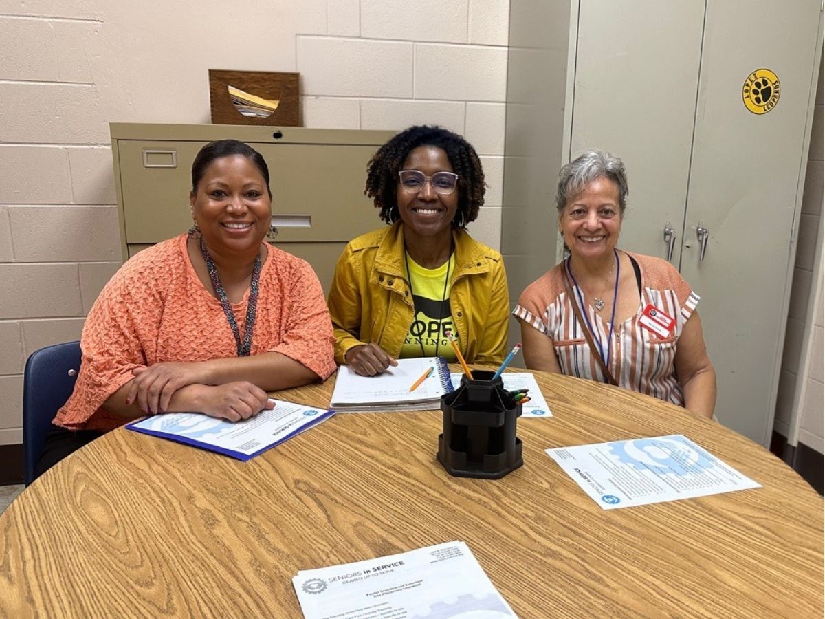 Classroom Grandparent volunteer Grandma Myrna and teacher Mrs. Litz pose together at an elementary school, celebrating a partnership that supports students and strengthens the school community.