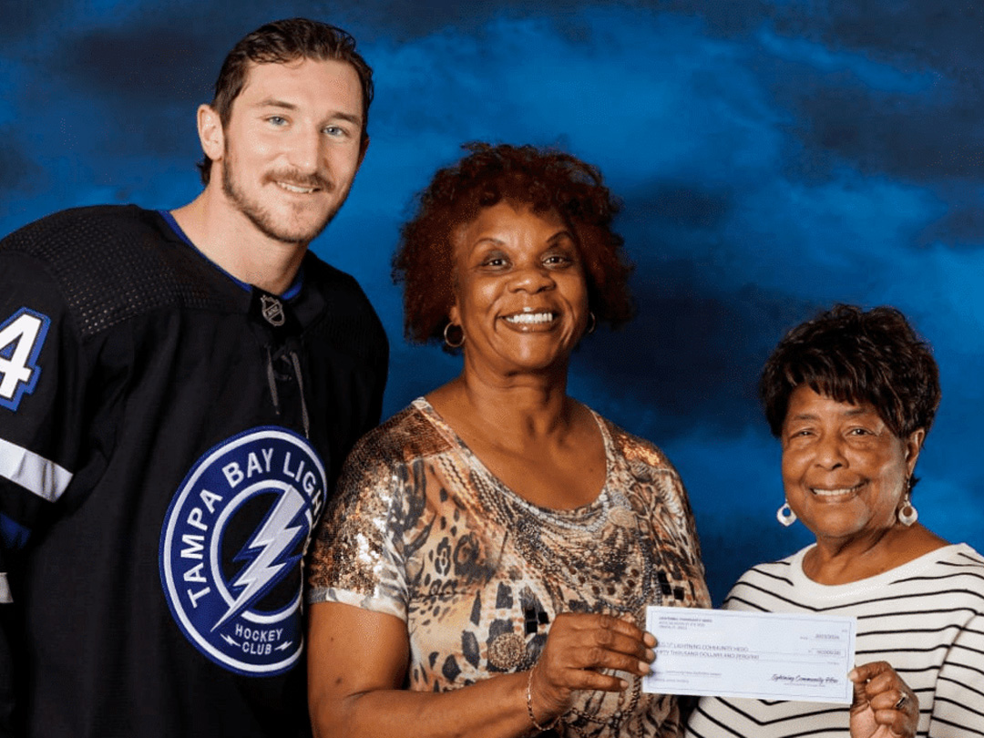 Classroom Grandparent volunteers accept a Tampa Bay Lightning Community Hero donation supporting students through the Readers in Motion program.