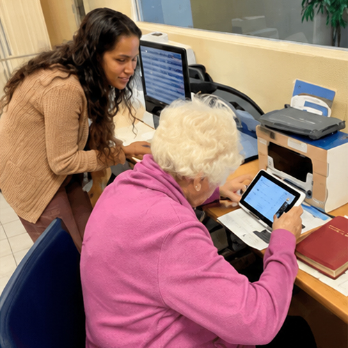 Tablet Assistance During Low-Vision Support Group A volunteer assists an older adult using a tablet during a low-vision support group meeting at Lighthouse for the Blind & Low Vision.
