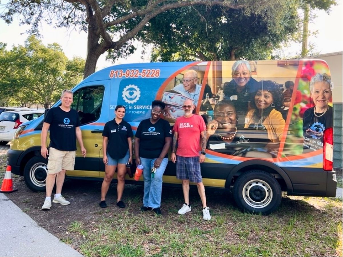 Mobile Outreach Team at Community Event Volunteers stand beside the Seniors in Service Mobile Outreach Van during a community outreach event in Tampa Bay.