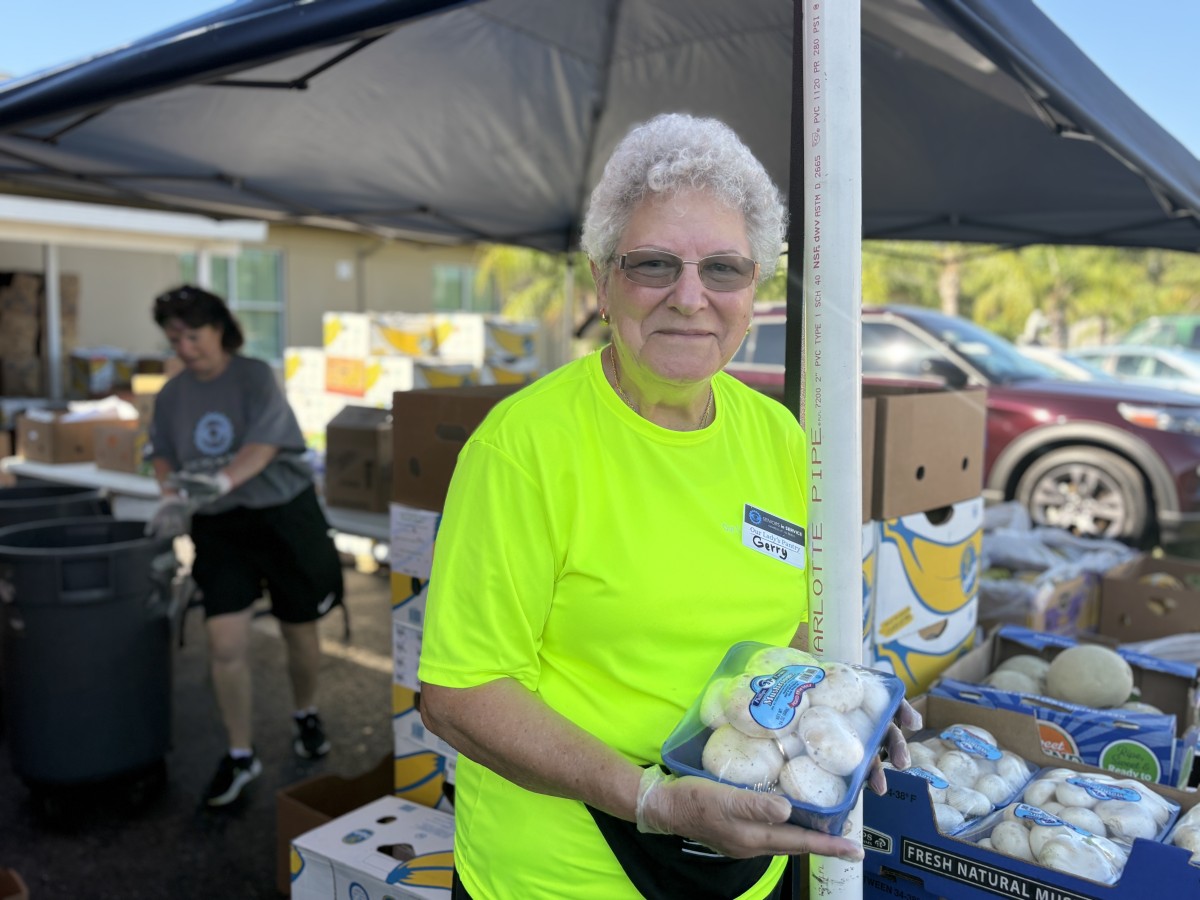 Gerry Holding Mushrooms at Food Pantry Seniors in Service volunteer shows fresh produce available at the Tampa Bay food pantry.